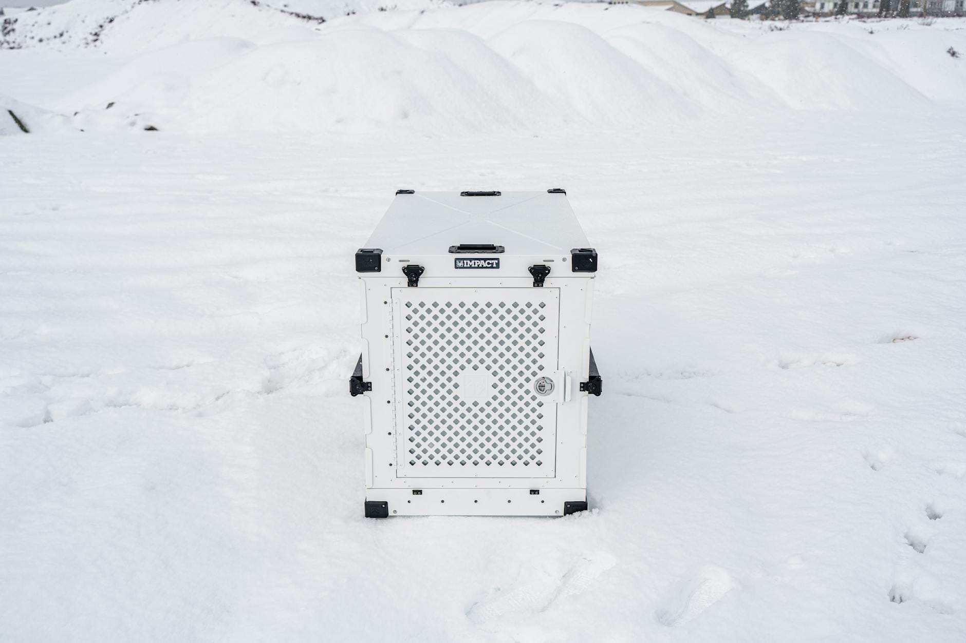 Biała klatka dla psa stojąca na zaśnieżonym podłożu