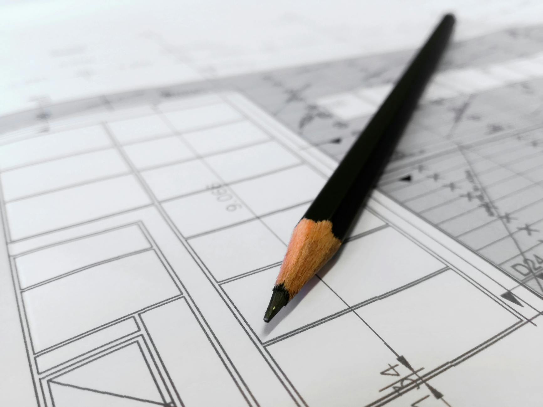 Czarny ołówek leżący na szczegółowych planach architektonicznych