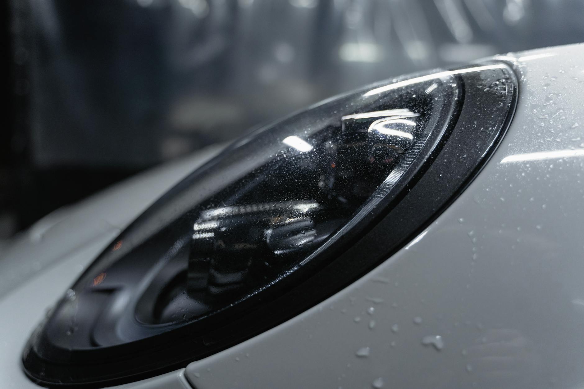 Zbliżenie reflektora samochodu pokrytego kroplami wody