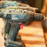 Akumulatorowe wiertarko‑wkrętarki ustawione w rzędzie na drewnianym stole