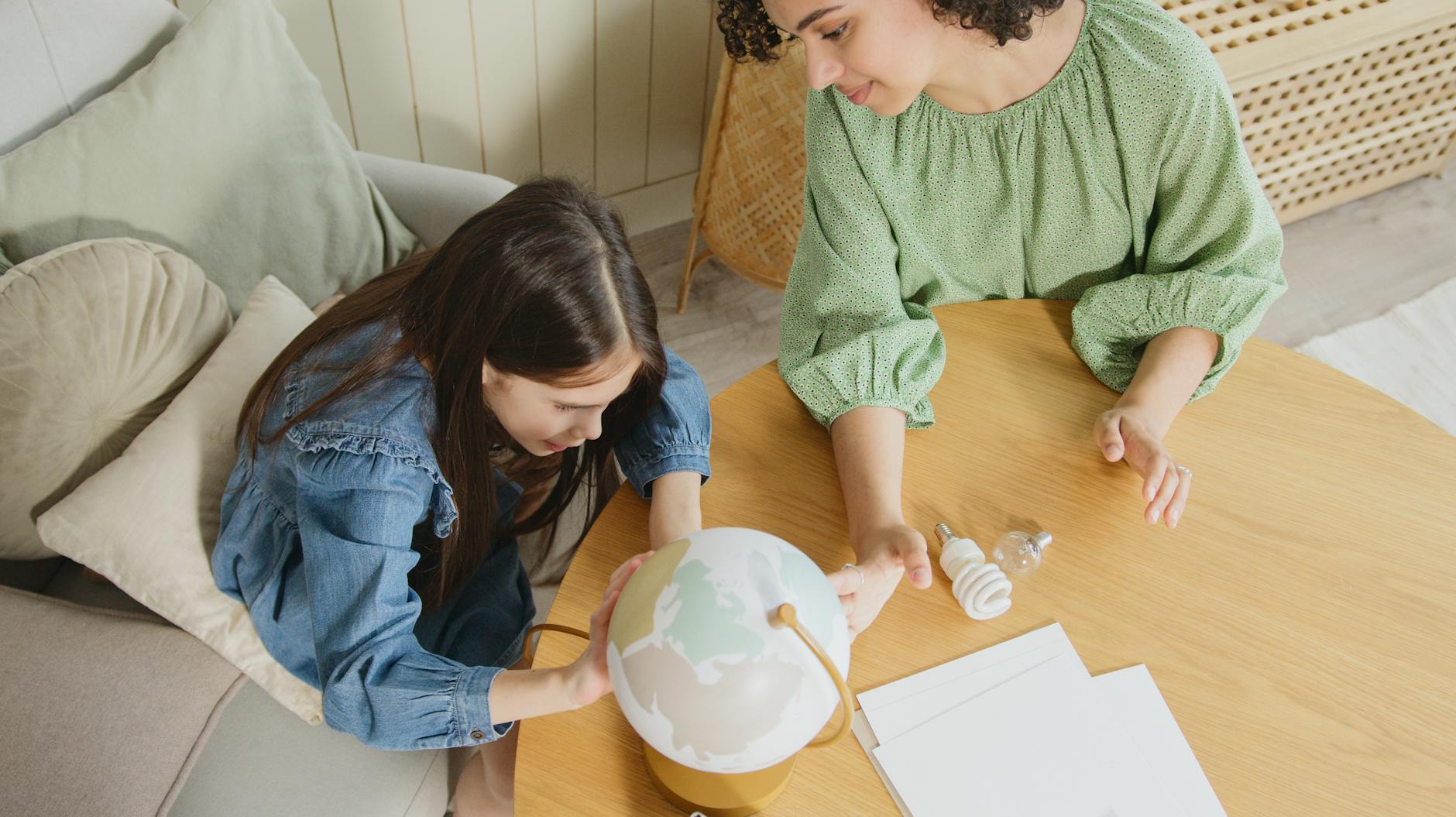 Mama z córką oglądają globus w domu, ucząc się o świecie i ekologii
