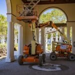 Podnośniki nożycowe elektryczne czy spalinowe: wybór pod posadzkę i teren Podnośniki nożycowe przy renowacji miejskiego budynku z łukami