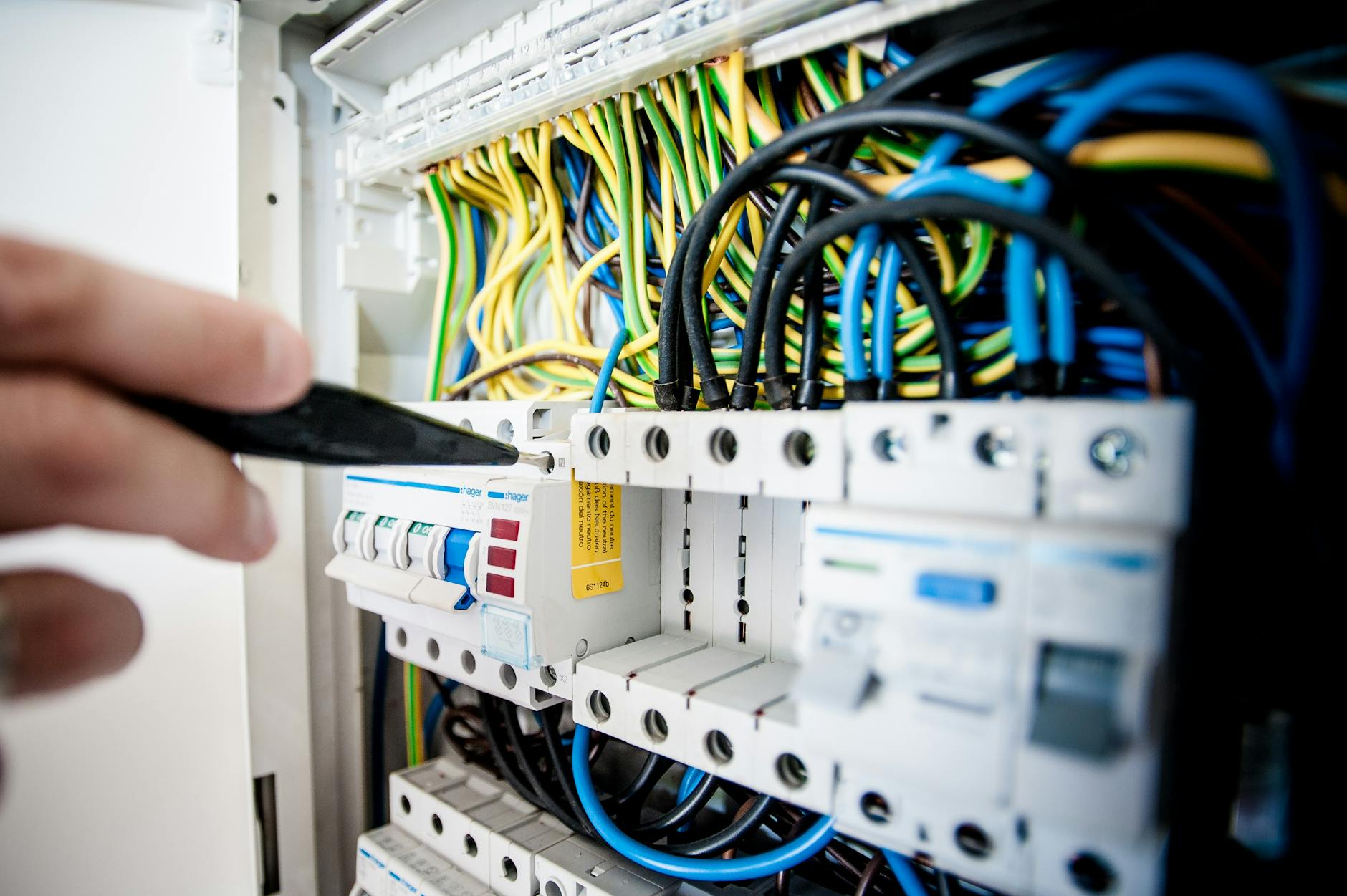Elektryk przy rozdzielnicy układa kolorowe przewody
