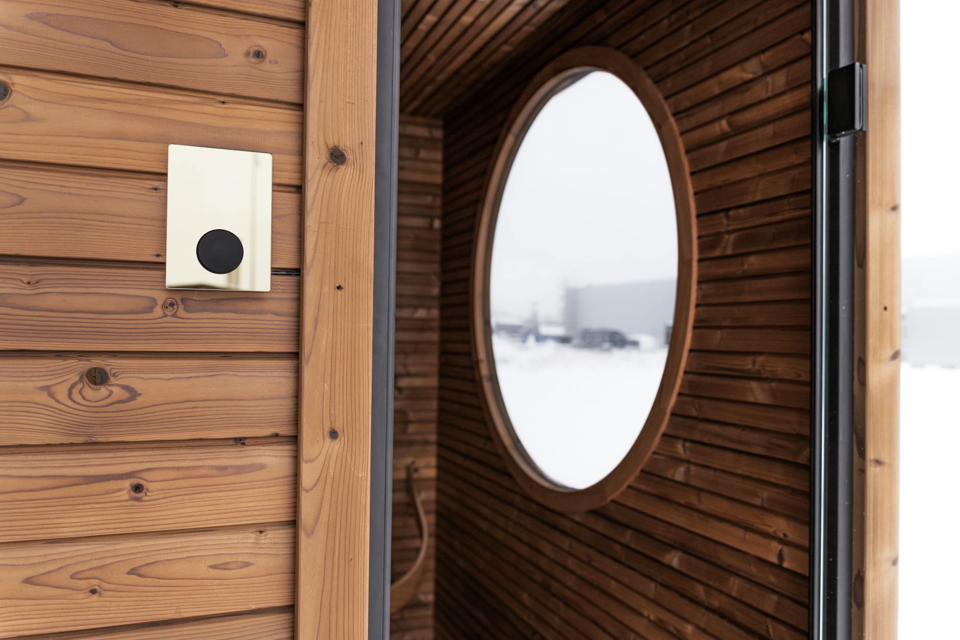 Drewniana sauna ogrodowa z okrągłym oknem i cyfrowym panelem sterowania