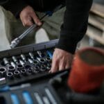 Mechanik w warsztacie wybiera nasadki do klucza z metalowej skrzynki