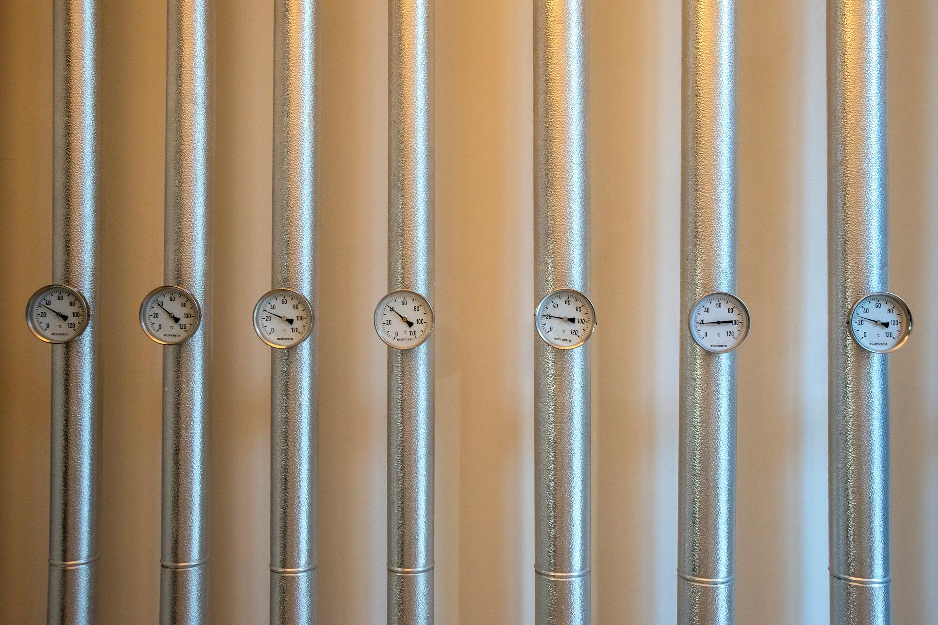 Srebrne rury instalacji z białymi manometrami w systemie ogrzewania